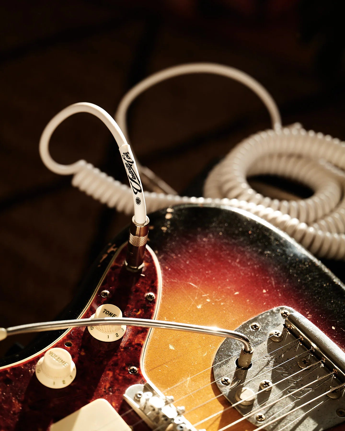 White coiled guitar cable with electric guitar amp